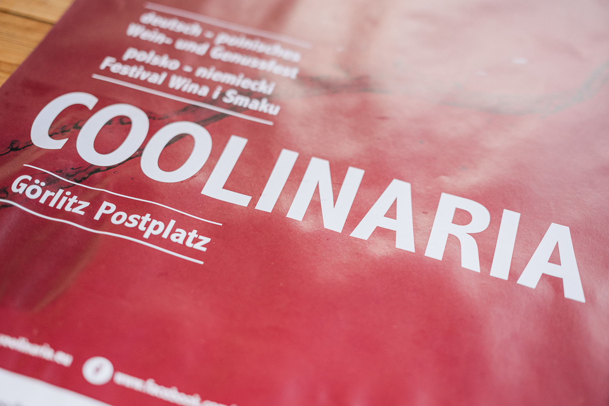 Eine Nahaufnahme eines leuchtend roten Coolinaria-Veranstaltungsplakats mit großer weißer Schrift COOLINARIA und darunter kleineren Angaben für den Postplatz Görlitz, wobei über dem Haupttitel zusätzliche Informationen zum Festival zu sehen sind.